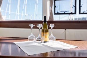 A table with a bottle of wine and four wine glasses on a white tablecloth.