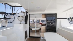 En lyxig inredning på en yacht med ett matområde, en sittgrupp och utsikt över hamnen.