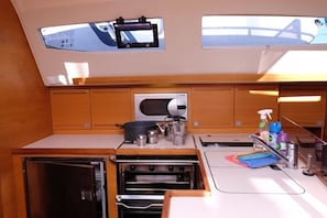 Eine kleine Kombüchenzeile mit Einbauofen, Mikrowelle und kleinem Kühlschrank.