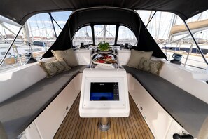 A boat's deck with a control panel, seating area, and a view of the marina. - Sibenik Sun-soaked Sailing: A Luxurious Croatian Voyage (Pirovac)