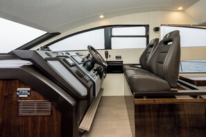 A boat interior with a control panel, seating area, and windows. - Sun-Kissed Sailing Adventure in Zadar, Croatia (Drage)