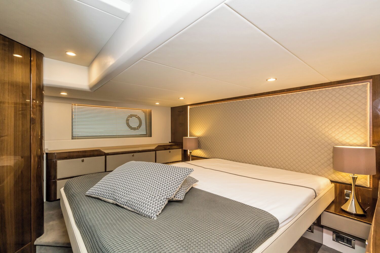 Une chambre moderne avec un lit, des tables de chevet, une tête de lit et une fenêtre avec des stores.