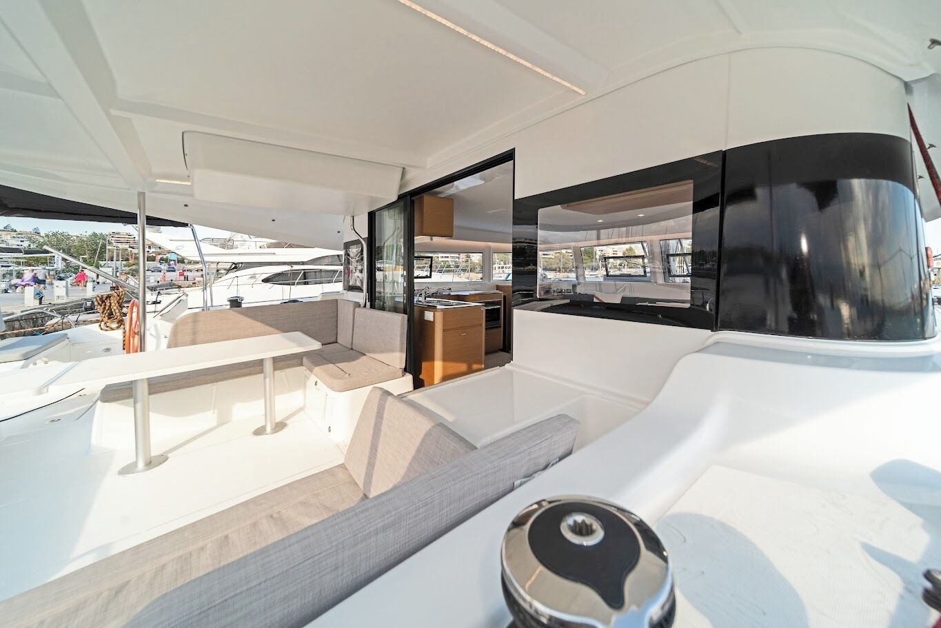 A modern boat interior with a dining area, a kitchen, and a seating area with a view of the marina.