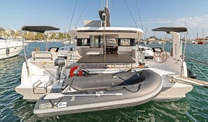 A sailboat with a covered seating area, a steering wheel, and a small inflatable dinghy. - Sun-kissed Sailing Adventure in the Ionian Islands (Preveza)