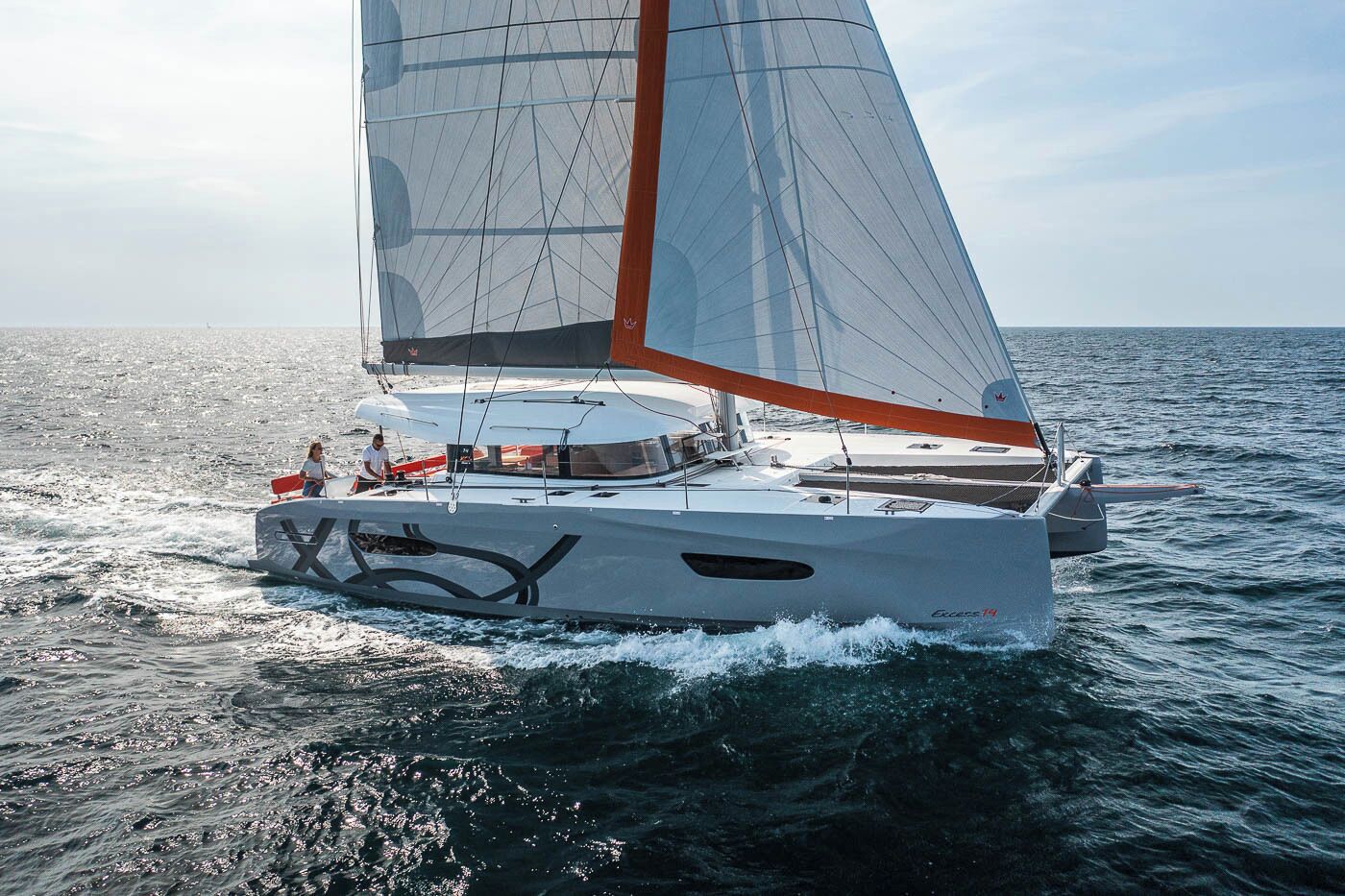 Een zeilboot met een kajuit en een persoon die aan de boeg staat.