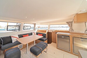 Ein kleines Boot mit Innenraum, Essbereich, Sitzgelegenheiten und einer kompakten Küche.