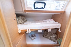 A compact, well-organized sleeping area with a bunk bed, a small table with a book, and a skylight above. - Sibenik Sun-soaked Sailing: A Luxurious Croatian Voyage (Pirovac)