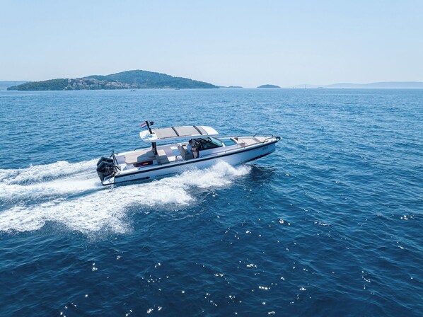 A speedboat on a calm sea with a distant island and clear skies.