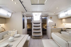 A compact, well-lit interior with a dining area, a kitchenette, and a bed. - Sun-Kissed Sailing Adventure in the Dodecanese Islands (Kos)