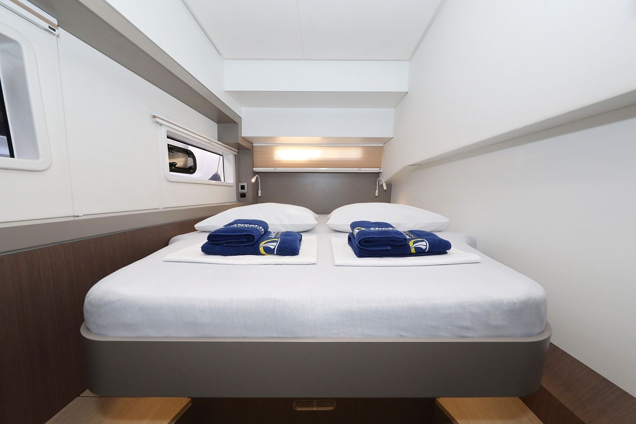 A compact, modern room with a bed, two pillows, and two neatly folded towels.