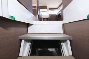 A compact kitchen area with a built-in stove, a small countertop, and a sliding door leading to a dining space. - Sun-Kissed Sailing Adventure in Zadar, Croatia (Biograd na moru)