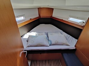 A compact sleeping area with a bed, pillows, and a window. - Sun-Kissed Sailing Adventure in Zadar, Croatia (Bibinje)