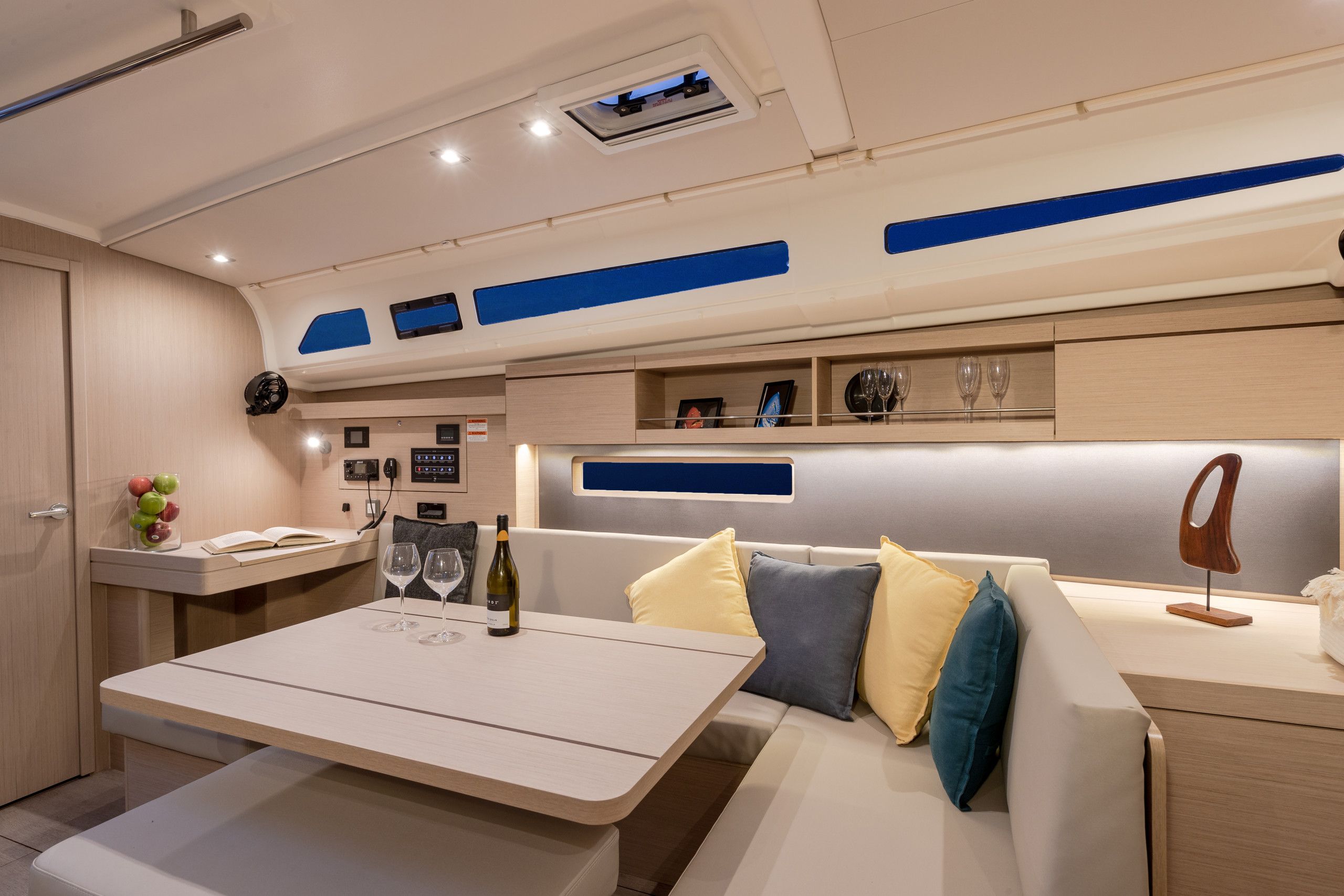 A modern interior with a seating area, a table with wine glasses, and a minibar.