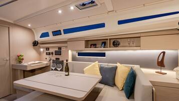 A modern interior with a seating area, a table with wine glasses, and a minibar.
