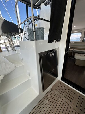A boat's interior with a seating area, a small refrigerator, and a view of the sea. - Sun-Kissed Sailing Adventure in the Ionian Islands, Lefkada (Lefkada)
