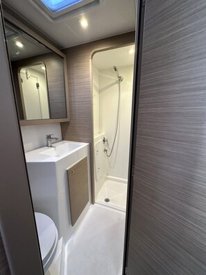 A compact bathroom with a shower, a sink, and a toilet. - Sun-Kissed Sailing Adventure in the Ionian Islands, Lefkada (Lefkada)