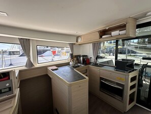 A compact kitchen with a stove, sink, and storage cabinets. - Sun-Kissed Sailing Adventure in the Ionian Islands, Lefkada (Lefkada)