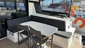 A boat's deck with a table and chairs, a grill, and a view of other boats. - Sun-Kissed Sailing Adventure in the Ionian Islands, Lefkada (Lefkada)