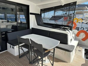 Ein Bootsdeck mit Tisch, Stühlen, einem Grill und Blick auf andere Boote.