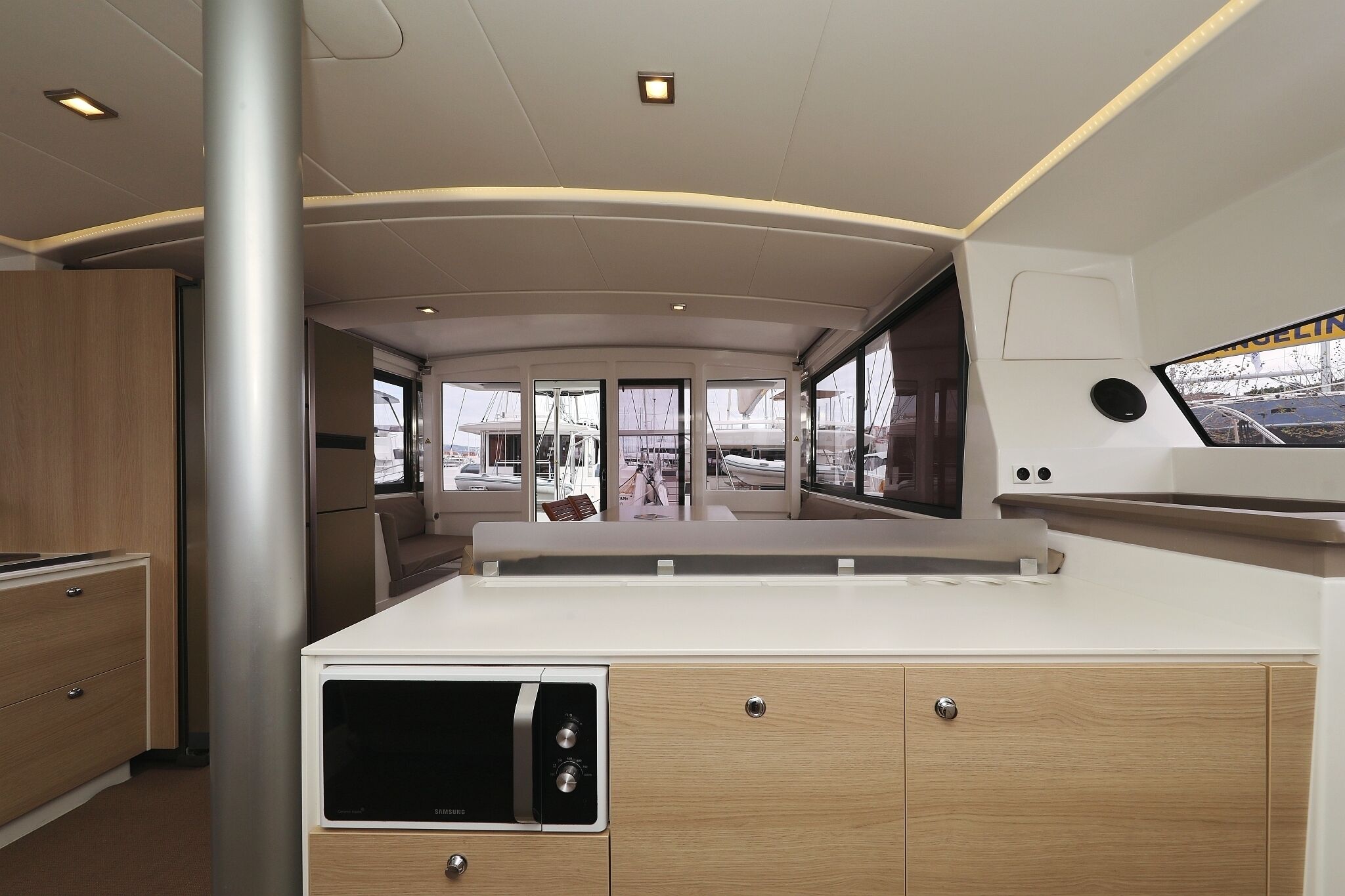 A modern kitchen with a built-in microwave, wooden cabinets, and a large window offering a view of the marina.
