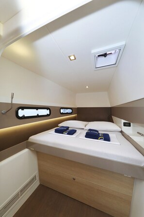 A compact, well-lit cabin with a bed, storage drawers, a small window, and a built-in heater. - Sun-kissed Sailing Adventure in Split-Dalmatia, Croatia (Trogir)