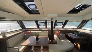 A boat interior with a dining area, seating, and a control station.