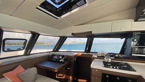 A compact galley with a stove, a small seating area, and a view of the sea. - Sun-Kissed Sailing Adventure in Distrito Riviere Noire, Mauritius (Black River)
