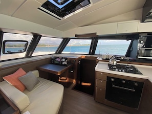 A compact galley with a stove, a small seating area, and a view of the sea. - Sun-Kissed Sailing Adventure in Distrito Riviere Noire, Mauritius (Black River)