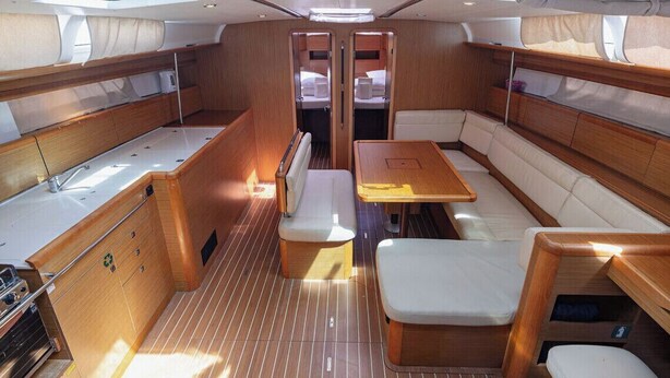 Interior de barco con comedor, asientos y cocina equipada con estufa.
