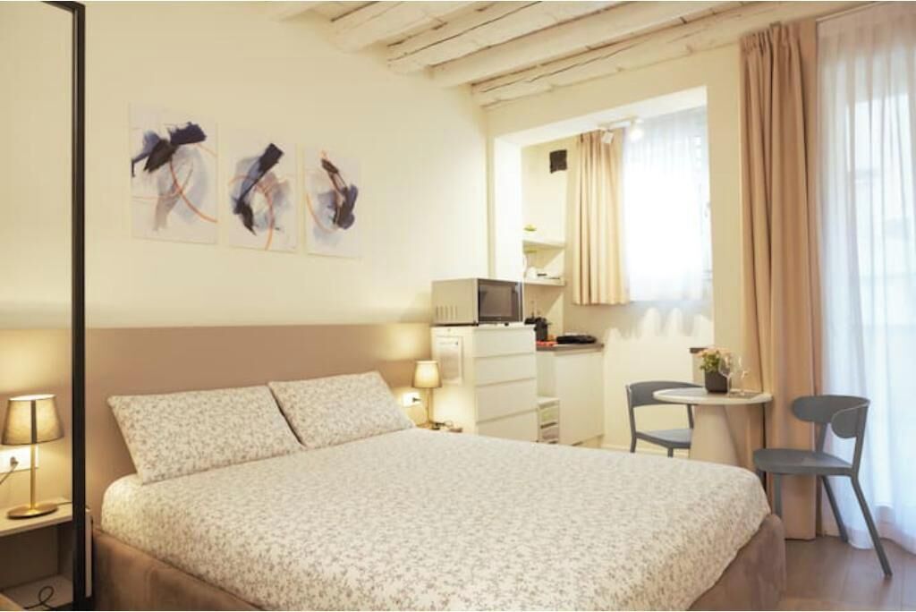 A hotel room with a bed, a desk, a chair, and artwork on the wall.