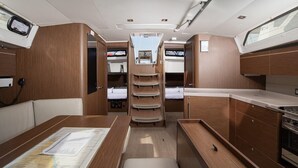 Un intérieur de camping-car compact comprenant un coin repas, un coin cuisine et une zone de couchage centrale avec un lit superposé.