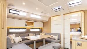 Un intérieur de camping-car moderne, doté d’un canapé modulable, d’une table à manger et d’une petite cuisine.