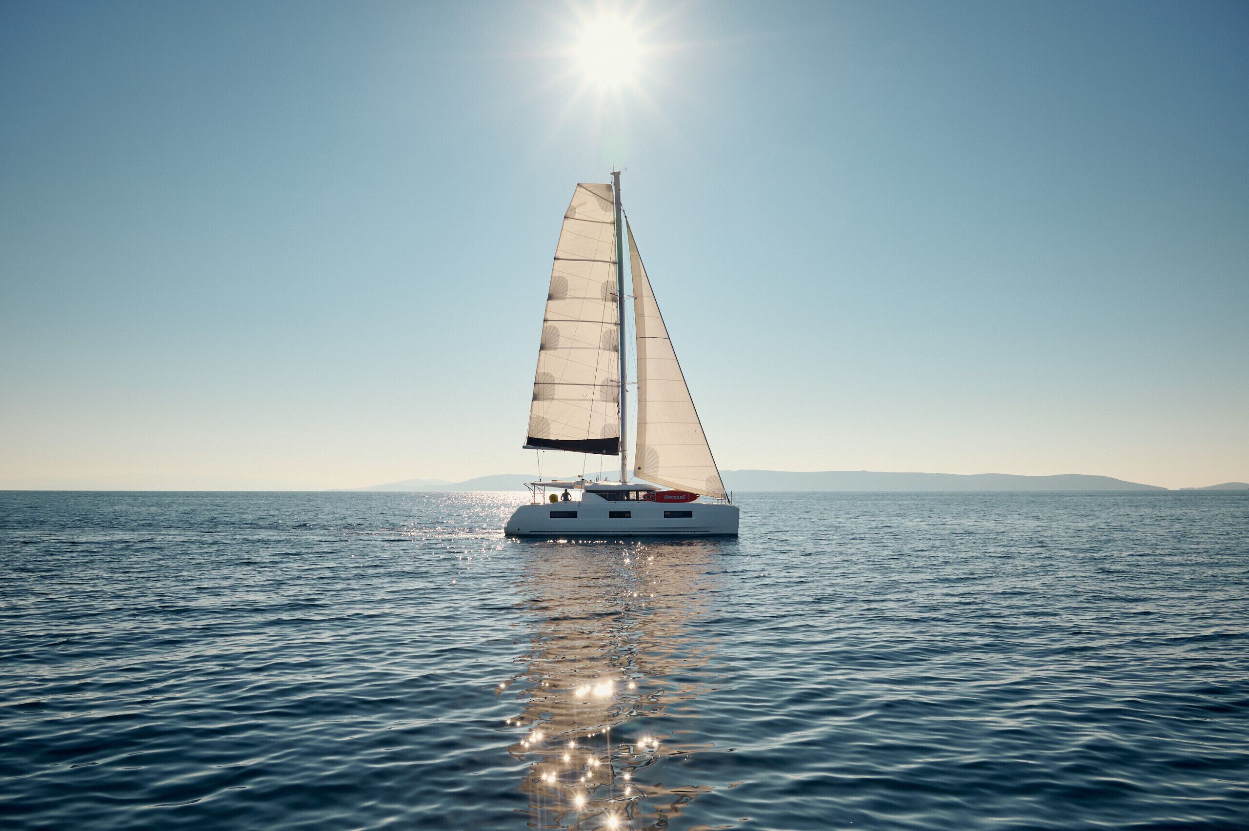 Ein Segelboot auf ruhigem Wasser unter blauem Himmel.