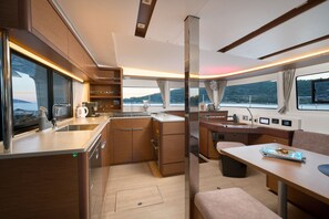 A modern kitchen with a large window, a dining area with a table and bench, and a view of the water outside.