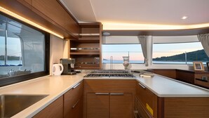 A modern kitchen with a large window, a built-in stove, and a sink. - Sun-kissed Sailing Adventure in Split-Dalmatia, Croatia (Trogir)