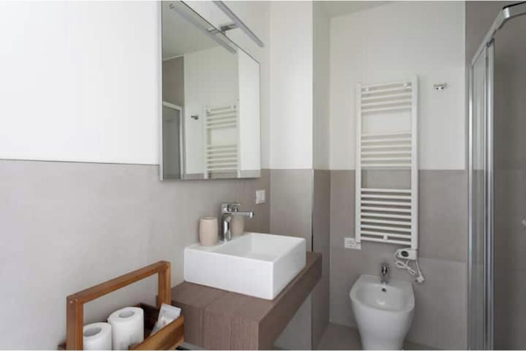 A modern bathroom with a rectangular sink, a mirror, a towel rack, and a bidet.