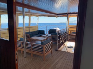 A deck with wooden furniture, a sofa, and a table.