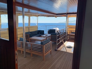 A deck with wooden flooring, a sofa, and a table.