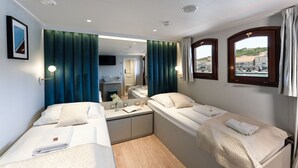 Hotellihuone, jossa on kaksi sänkyä, pieni työpöytä, peili ja televisio.