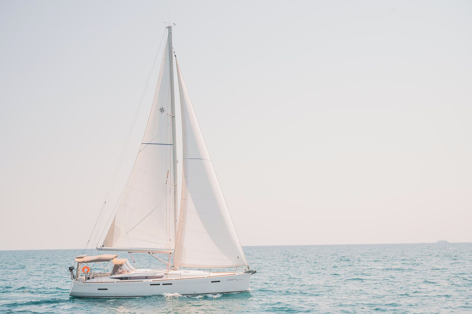 A sailboat with a white hull and a single mast, sailing on calm waters.