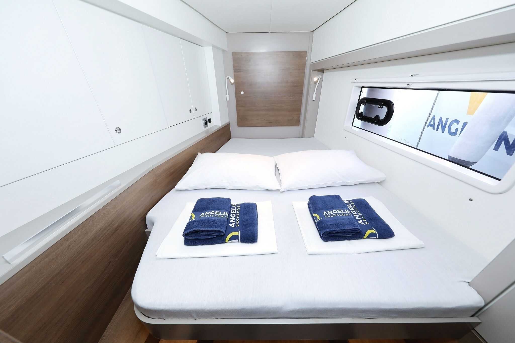 Een knus, privé-hutje met een bed, twee handdoeken, een houten wandpaneel en een raam met uitzicht.
