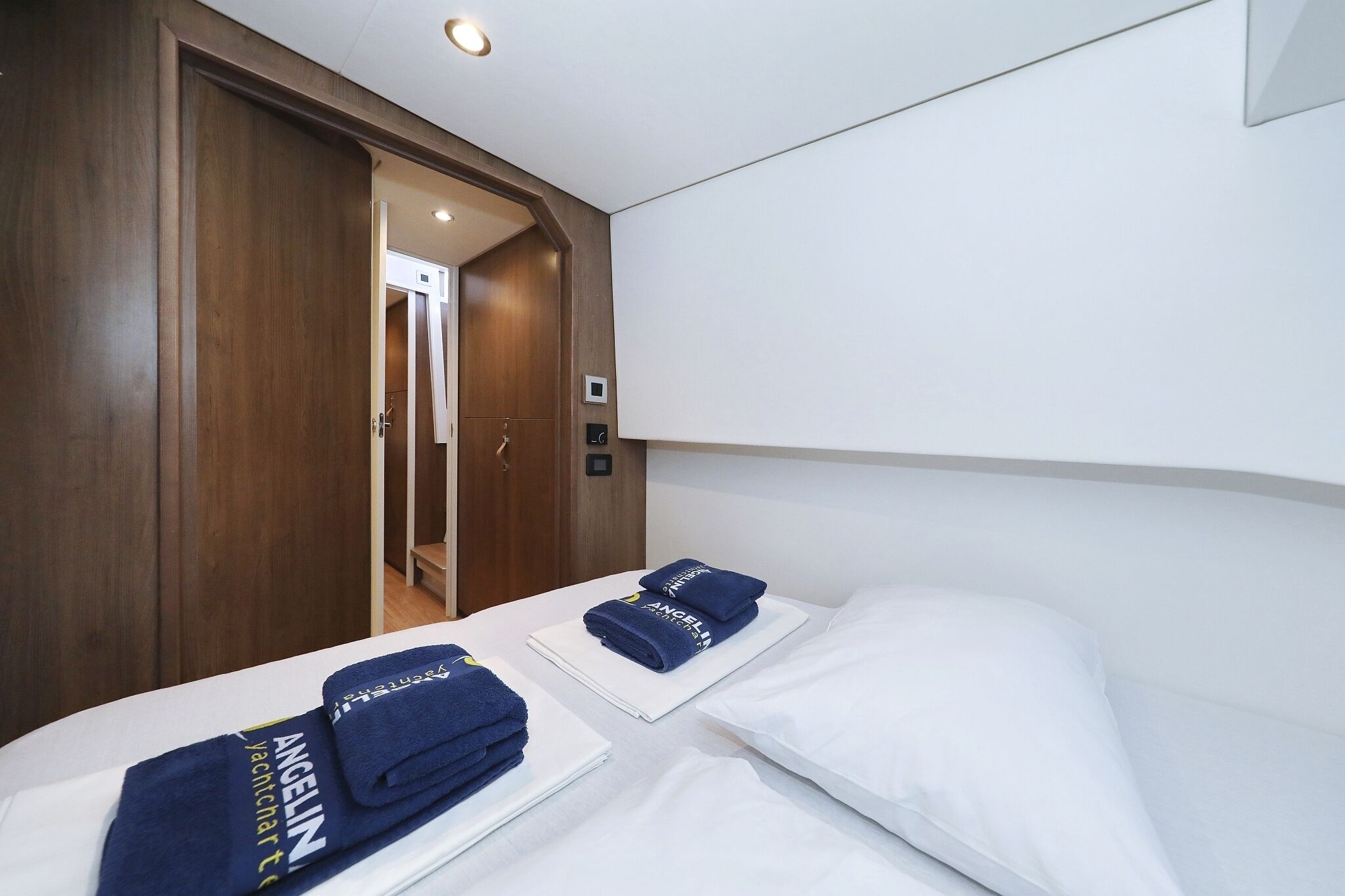 Habitación de hotel con dos camas, un armario de madera y una puerta que da a otra habitación.