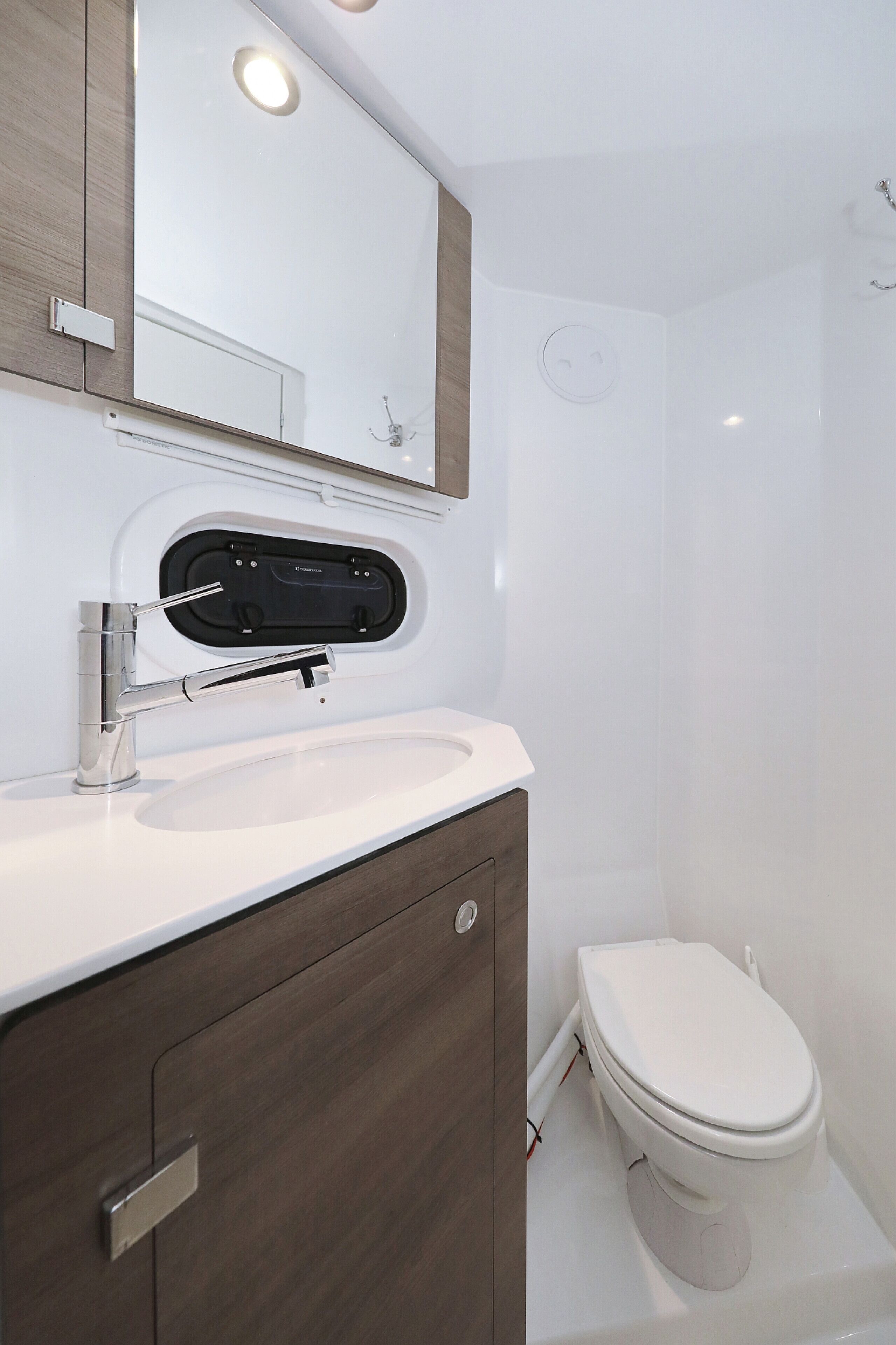 A modern bathroom with a white sink, a mirror, and a toilet.