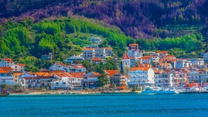 A coastal town with buildings, a harbor, and terraced hills.