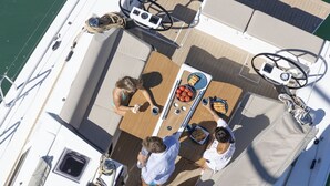 A boat deck with a dining table, chairs, and a steering wheel. - Sun-Kissed Sailing Adventure in Galicia, Baiona (Baiona)