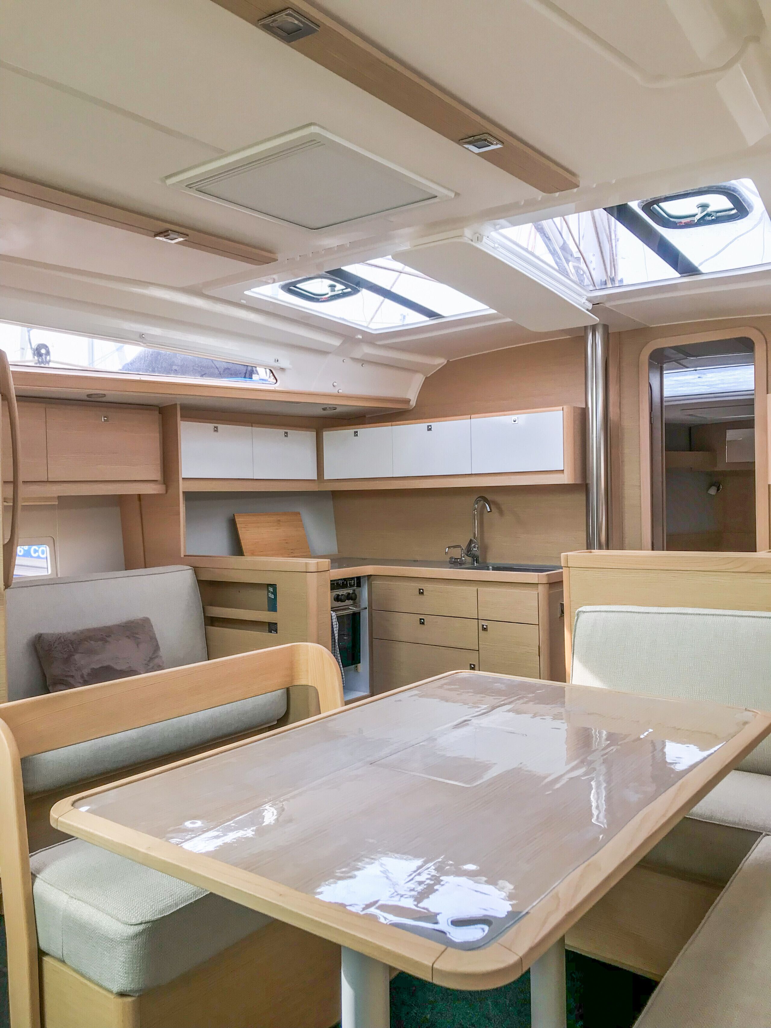 Interior compacto de una caravana con cocina americana, comedor y baño pequeño.