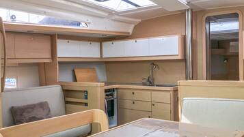 Interior compacto de una caravana con cocina americana, comedor y baño pequeño.