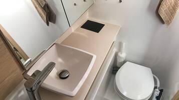 Un baño pequeño con lavamanos, inodoro y espejo.