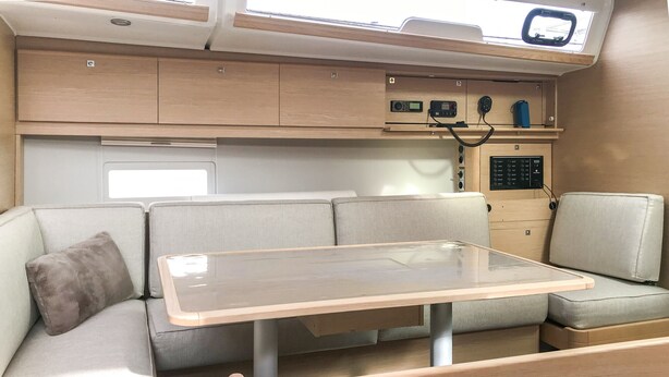 A compact living space with a table, cushioned seating, and a control panel with various buttons and a display.