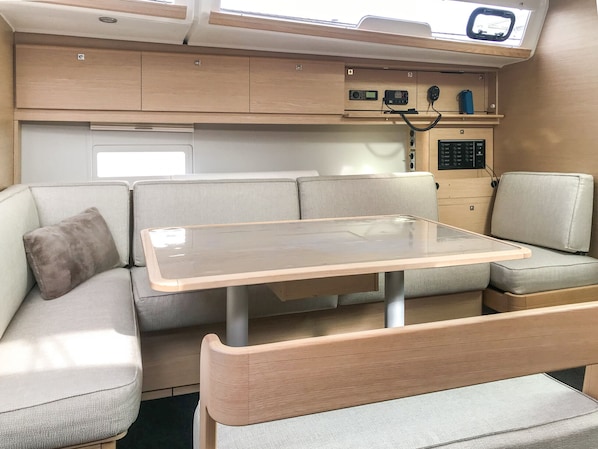 A compact living space with a table, cushioned seating, and a control panel with various buttons and a display.